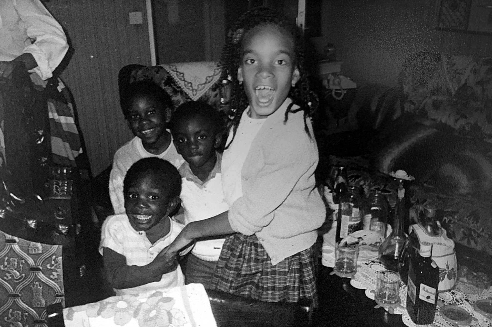 Photo de famille en noir et blanc : quatre enfants rient autour d'une table de fête